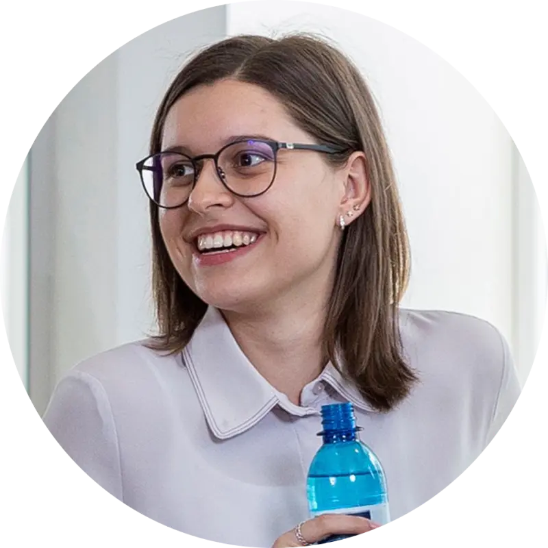 Eine junge Frau mit Brille lächelt und hält eine Selters Wasserflasche in der Hand.